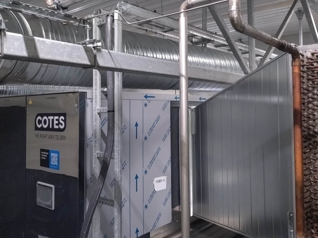 Teknisk rom med ventilasjonskanal horisontalt oppunder taket, adsorpsjonsavfukter (til venstre) og kanal inn til avfukteren med kjølebatteri til høyre.