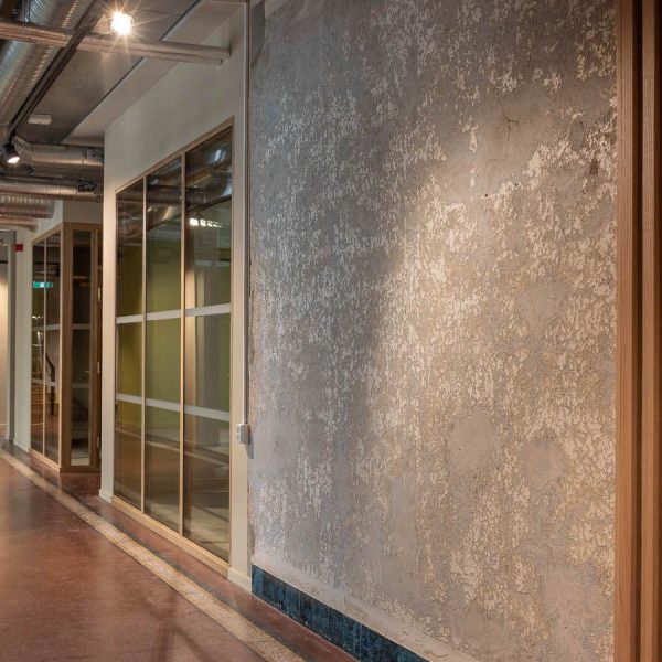 Bilde av korridor med glassvegg inn til møterom og ventilasjonskanaler i taket