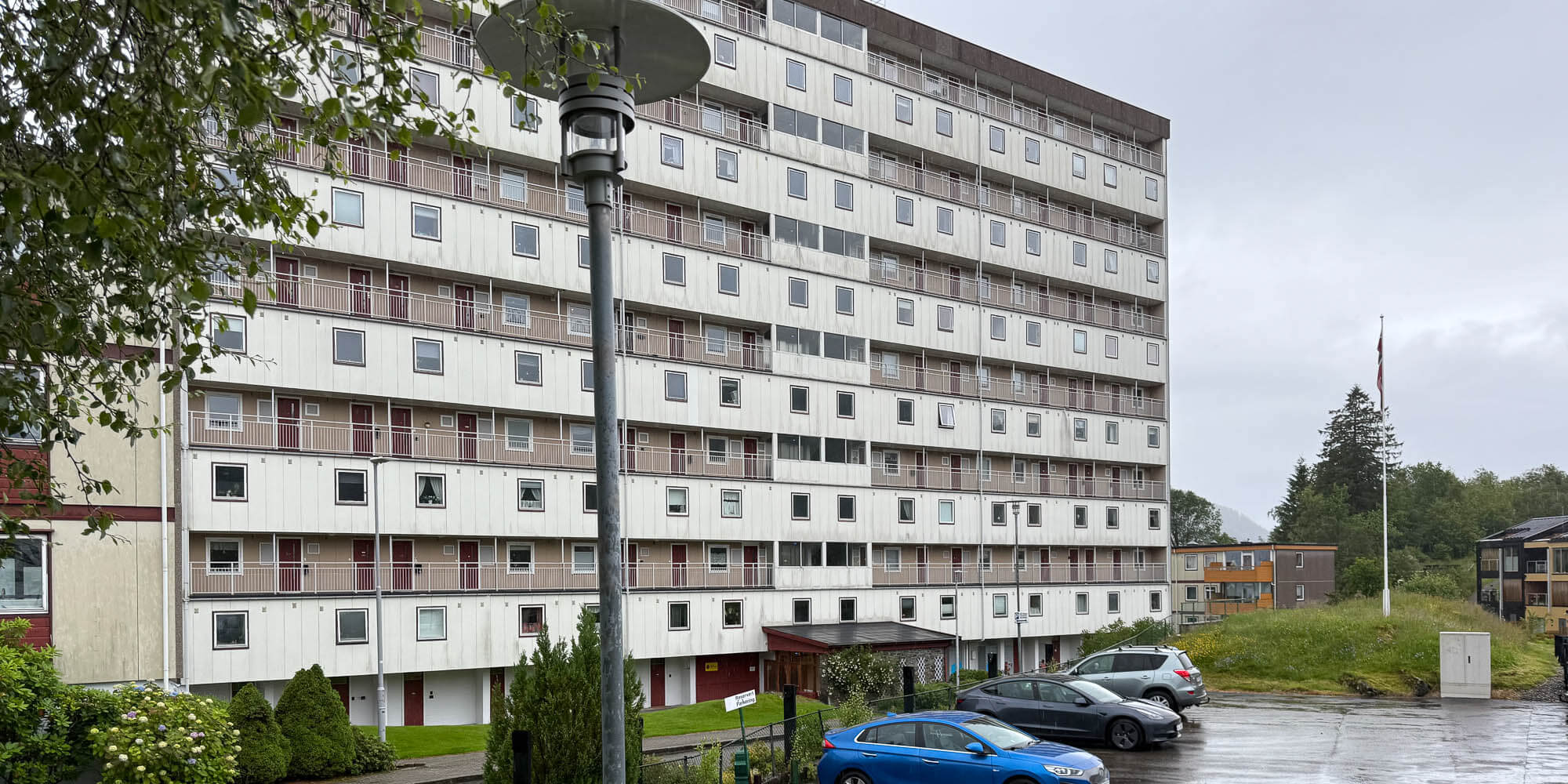 Fasade Vilhelm Bjerknesvei med biler parkert foran og en lyktestolpe i forgrunnen.