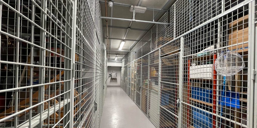 En lang rekke med boder med nettingvegger innover til en avfukter som henger på veggen innerst.