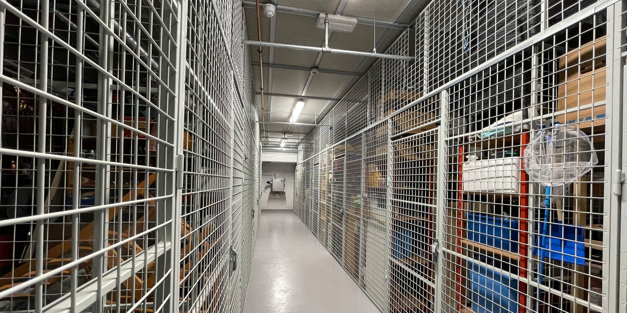 En lang rekke med boder med nettingvegger innover til en avfukter som henger på veggen innerst.