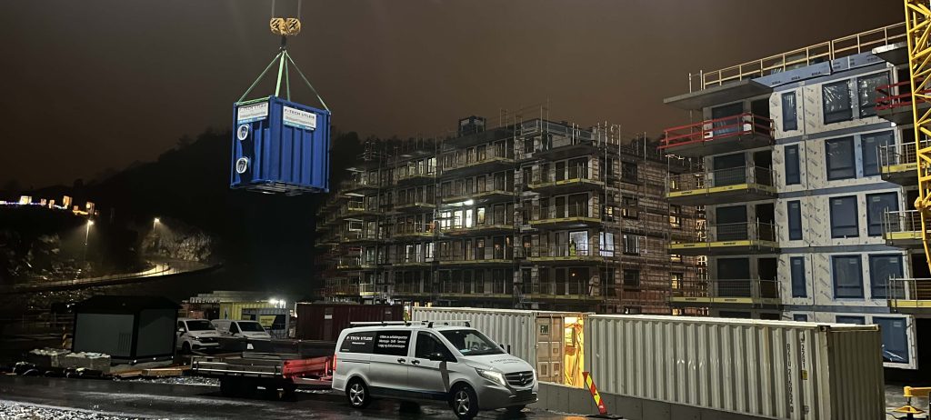 Container med avfukter til byggtyørk heises på plass på tredje leilighetsbygg ved JM Norges byggeprosjekt på Ørnafjellet.