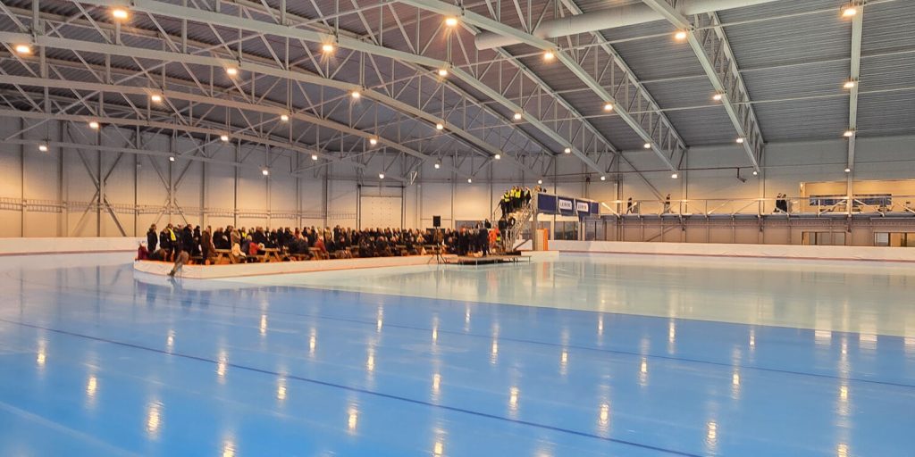 Forsamling i enden av banen i Stord ishall under offisiell åpning, med speilblank is i forgrunnen