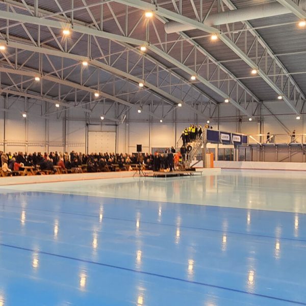 Forsamling i enden av banen i Stord ishall under offisiell åpning, med speilblank is i forgrunnen