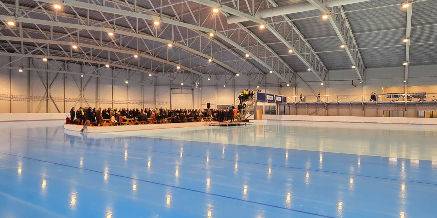 Forsamling i enden av banen i Stord ishall under offisiell åpning, med speilblank is i forgrunnen